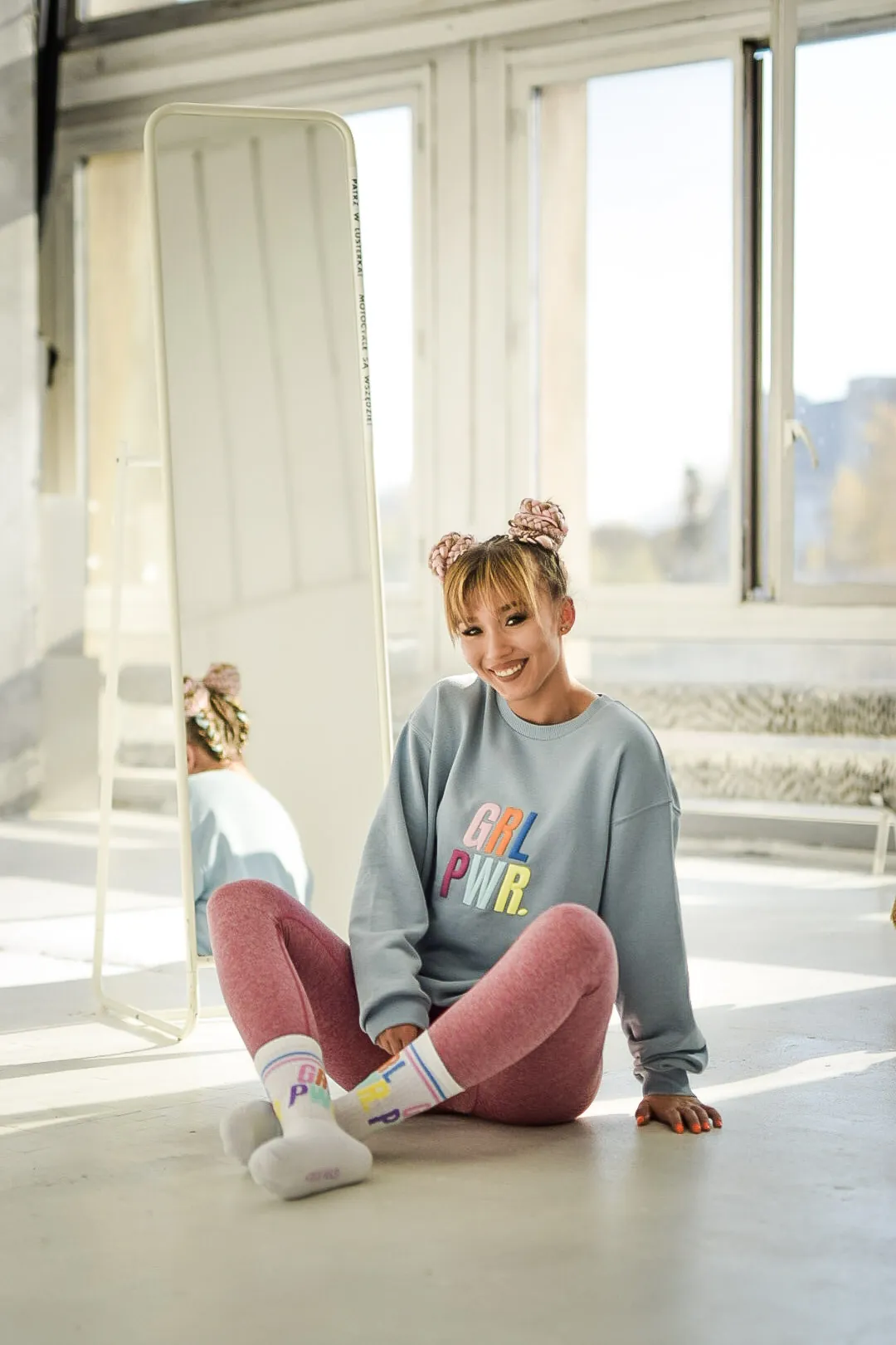 Kobieta w jasnym studiu przy lustrze, bluza GRL PWR